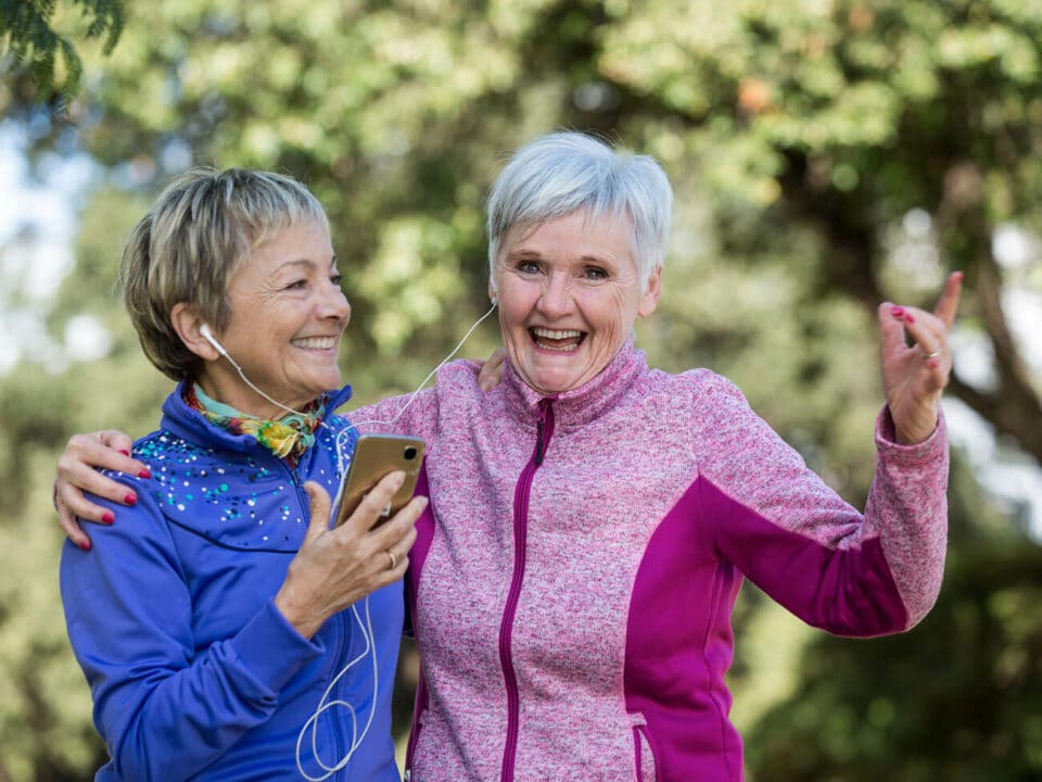 senior women in exercise attire, dancing and listing to music on earbuds