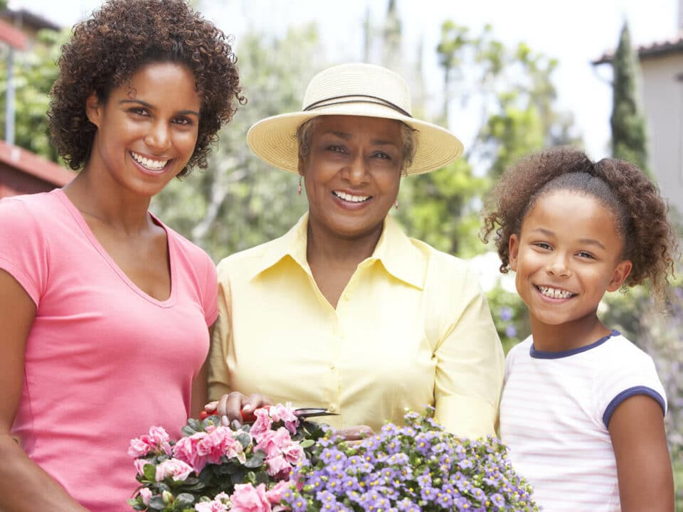 three females standing together, holding flowers and smiling