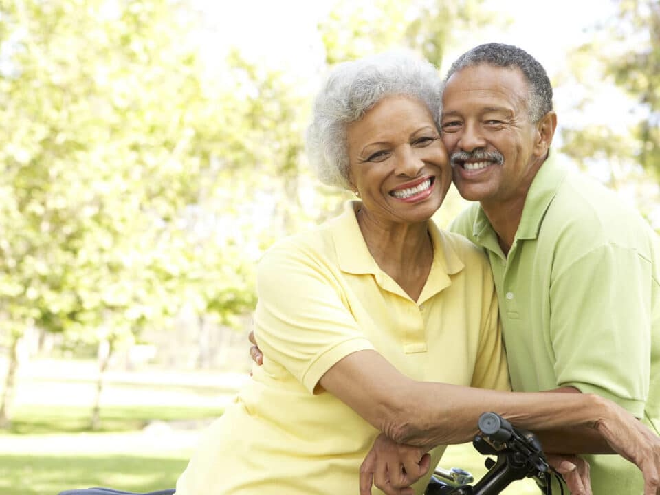 african american couple smiling, cheek to cheek, resting on a bike