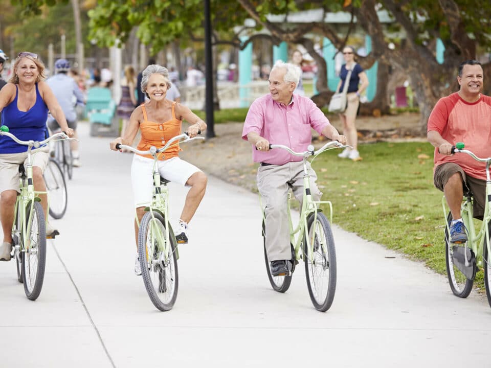 two men and two women smiling and riding bikes on busy pathway