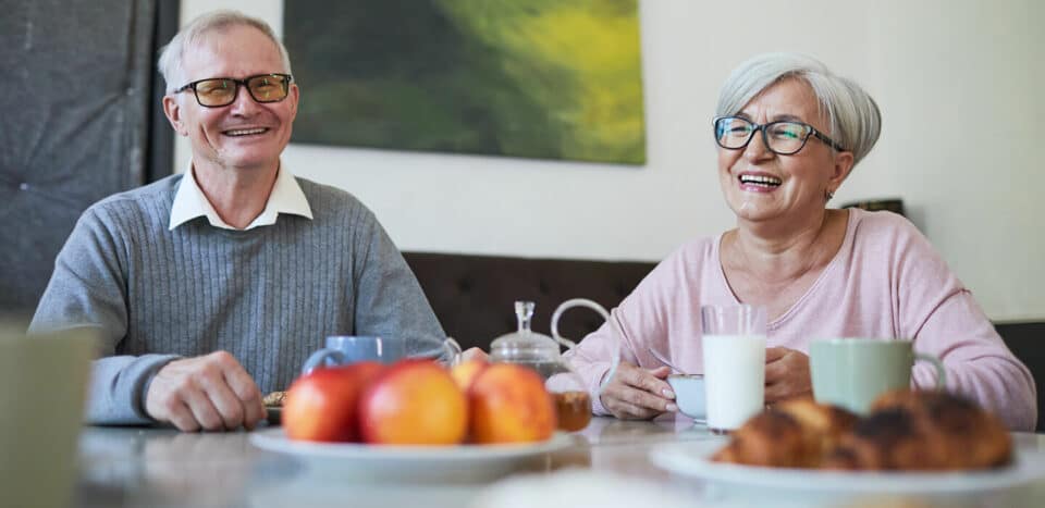 woman and man at a breakfast table wearing glasses and smiling