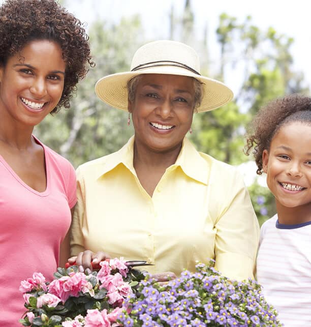 three females standing together, holding flowers and smiling