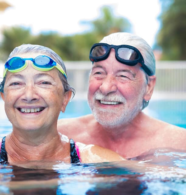 man and woman with googles on their heads in a pool smiling