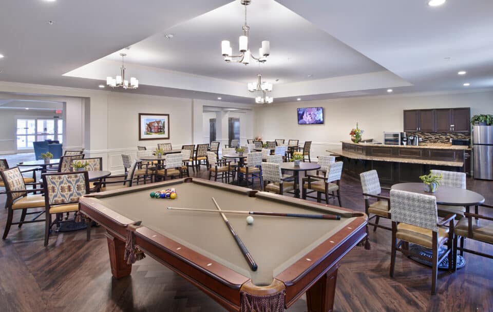 billiards table with pool cues, tables and chairs for dining and bar