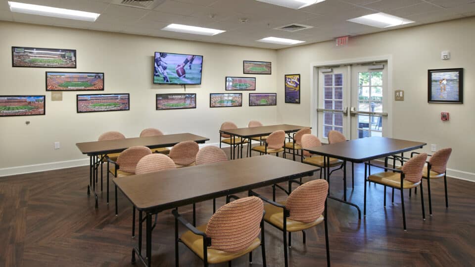 four long tables with chairs; football stadium photos and tv; exit door